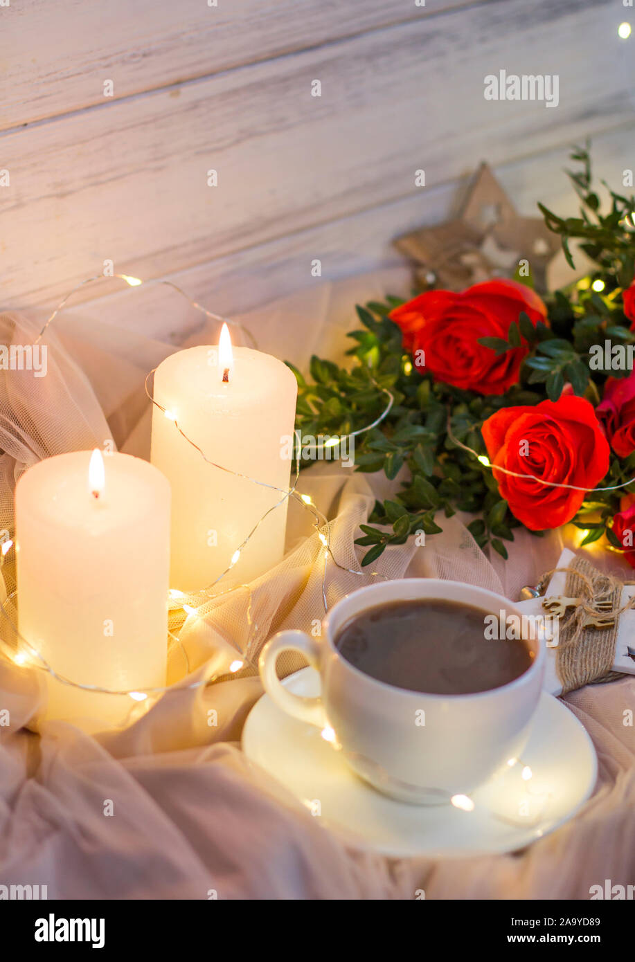 Composition: red roses with boxwood, garlands, candles, star and cup coffee (tea) Stock Photo