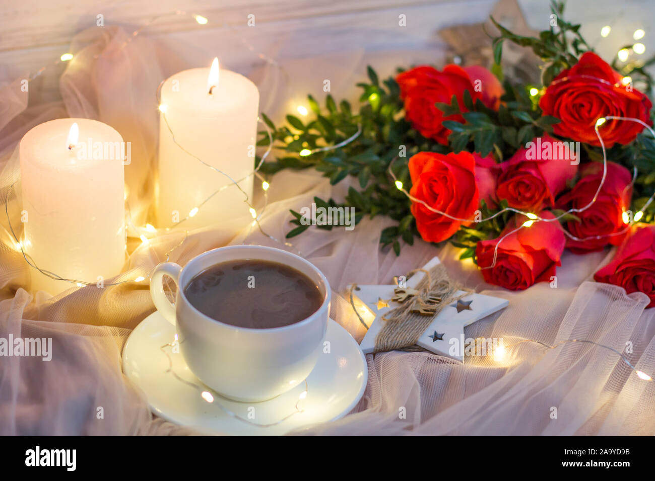 Composition: red roses with boxwood, garlands, candles, star and cup coffee (tea) Stock Photo
