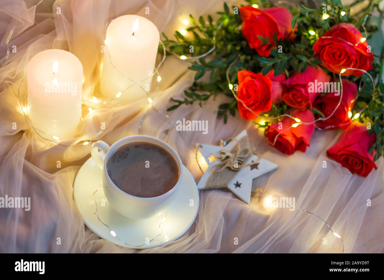 Composition: red roses with boxwood, garlands, candles, star and cup coffee (tea) Stock Photo