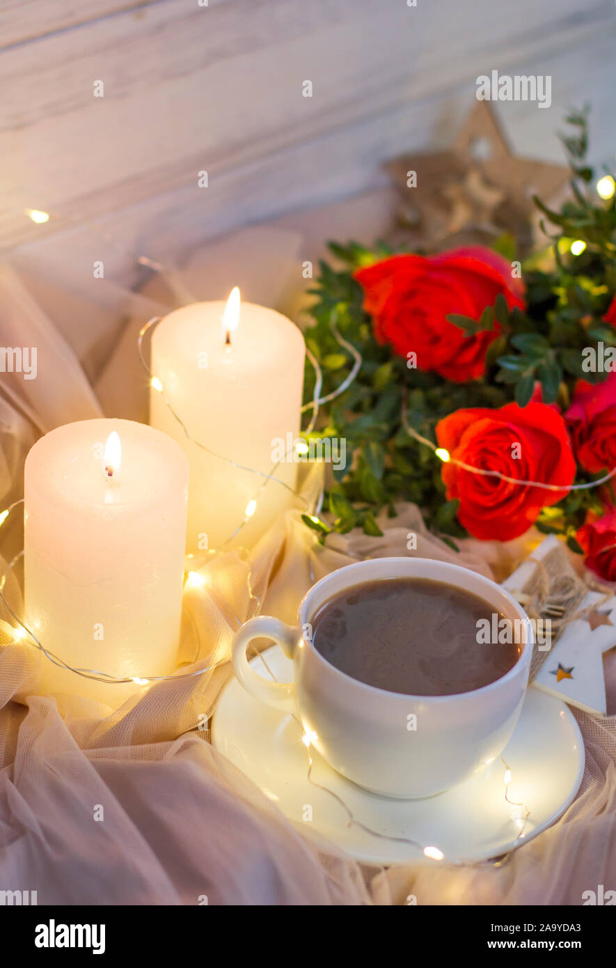 Composition: red roses with boxwood, garlands, candles, star and cup coffee (tea) Stock Photo
