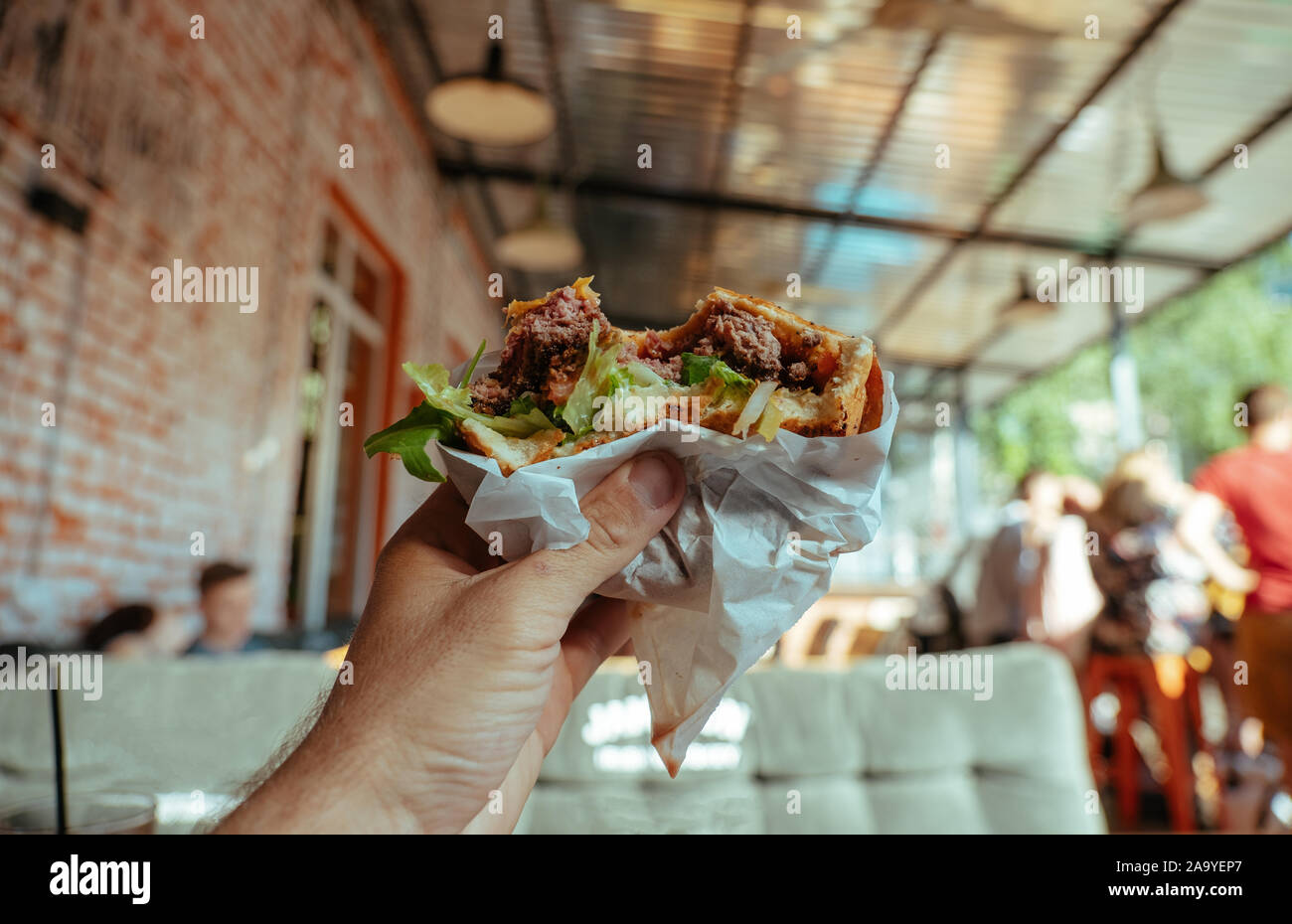 Tasty Hamburger with ham and salad in the man's hand Stock Photo
