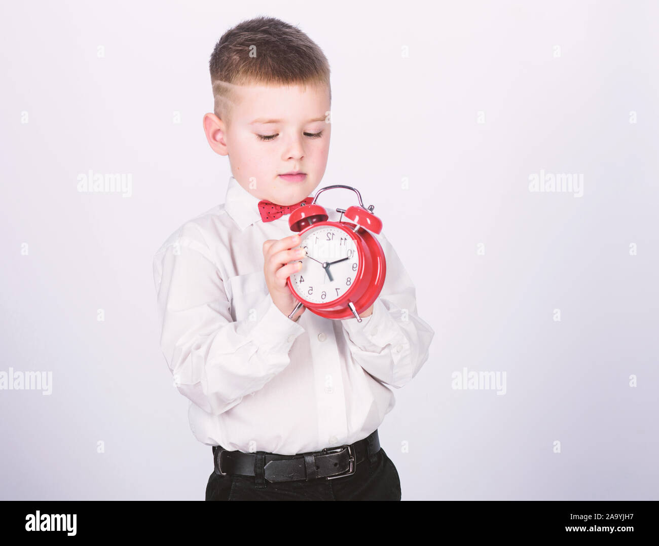 Set up alarm clock. Child little boy hold red clock. It is time