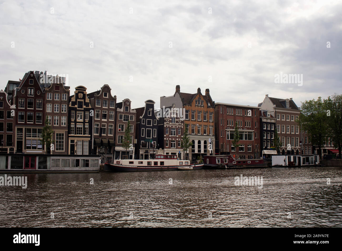 View of Amstel river, canal boat houses and historical, traditional and typical buildings reflecting Dutch architectural style in Amsterdam. It is a s Stock Photo