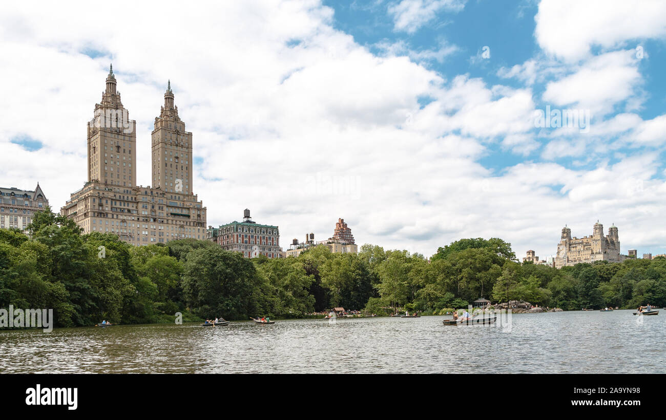 People rowing on the Lake in Central Park with the San Remo building in the background on a sunny summer day Stock Photo