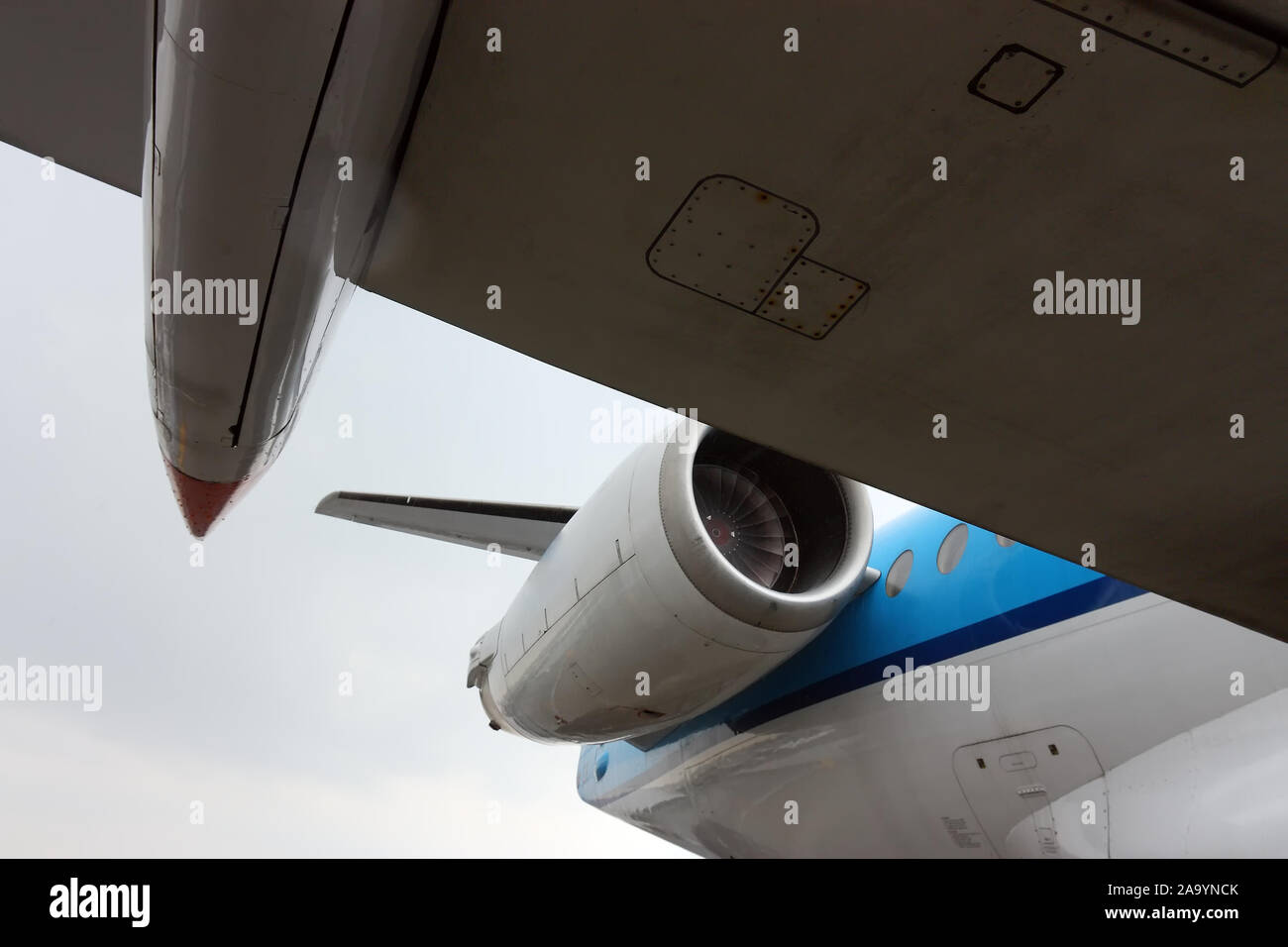 View from under the wing of an white and blue large airplane with jet engine Stock Photo