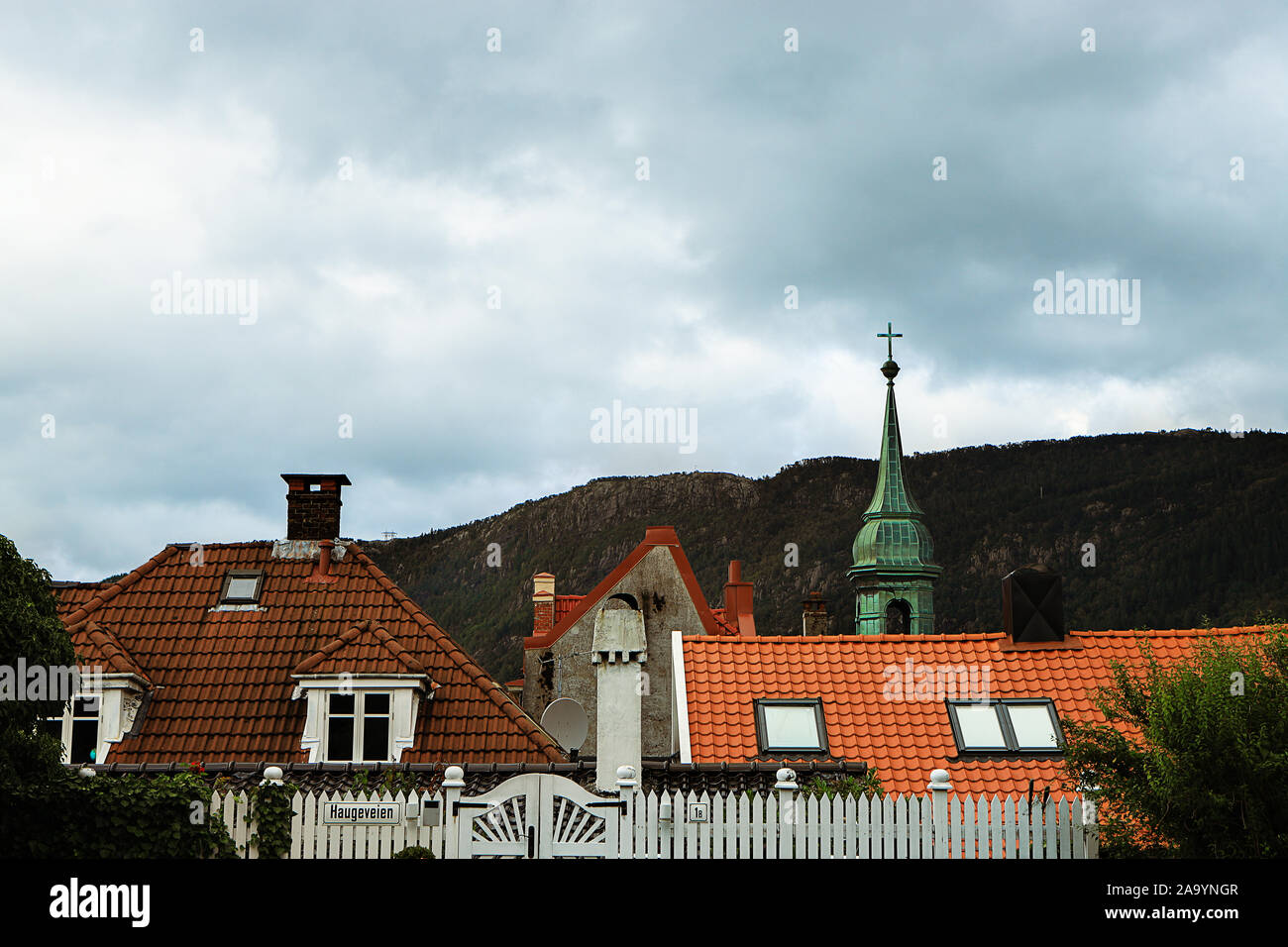 Picturesque rooftops in Bergen old town. Mountains, clouds, wooden ...