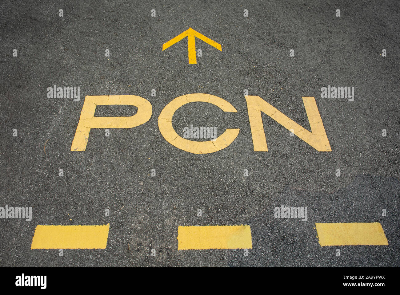 Yellow 'PCN' sign and lines on asphalt road Stock Photo