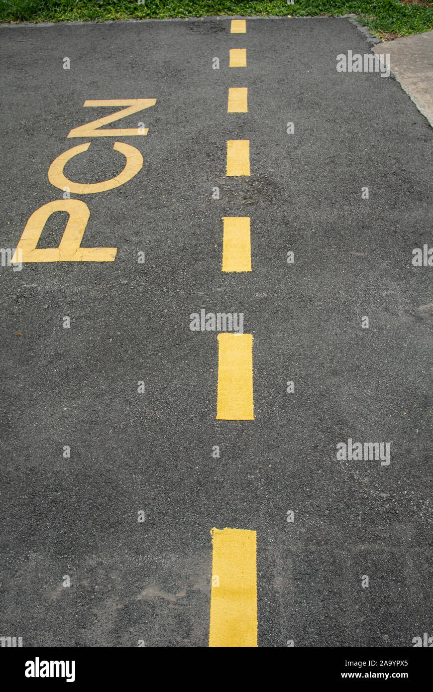 Yellow 'PCN' sign and lines on asphalt road Stock Photo