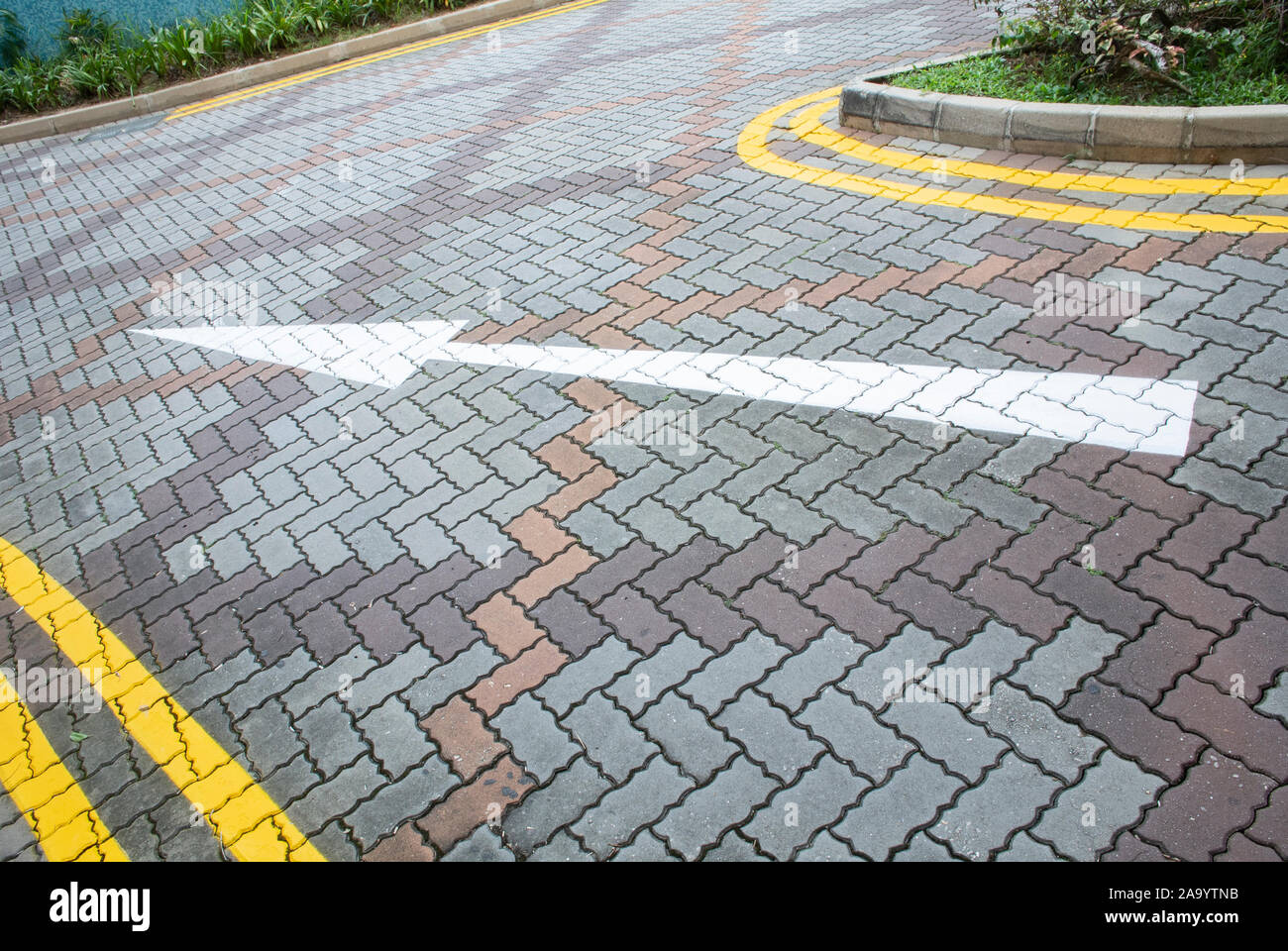White arrow and double yellow lines painted on interlocking concrete ...