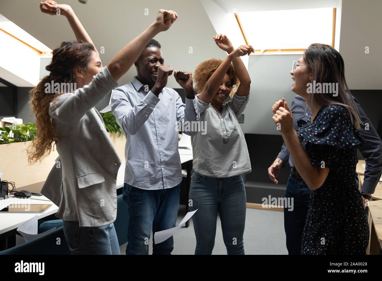 Overjoyed multiracial team members enjoying party in modern coworking office. Stock Photo