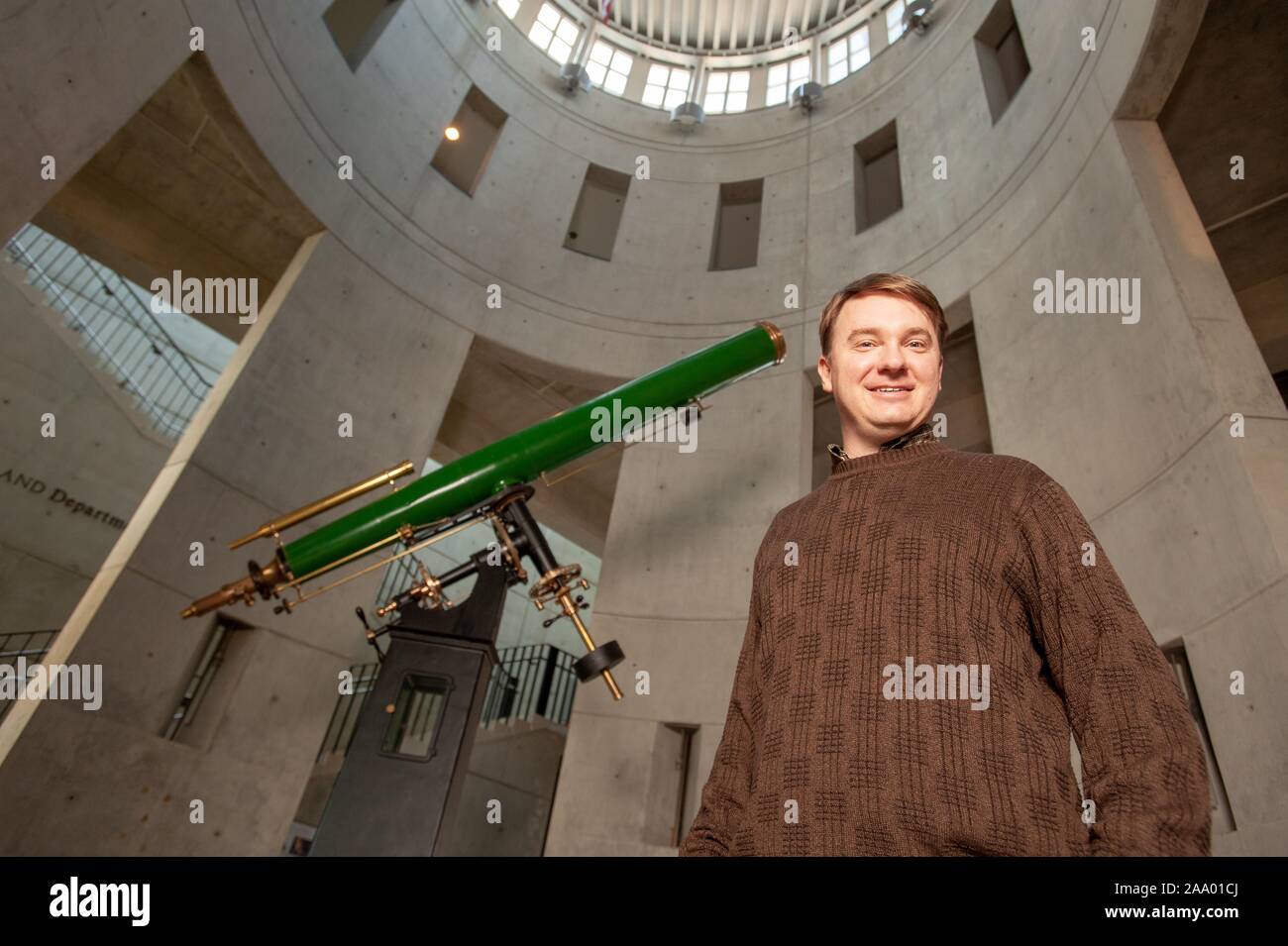 Low-angle shot of David Thilker, a Principal Research Scientist in the Henry A Rowland Department of Physics and Astronomy, standing in an observatory next to a telescope and smiling at the camera, at the Johns Hopkins University, Baltimore, Maryland, February 13, 2009. From the Homewood Photography Collection. () Stock Photo