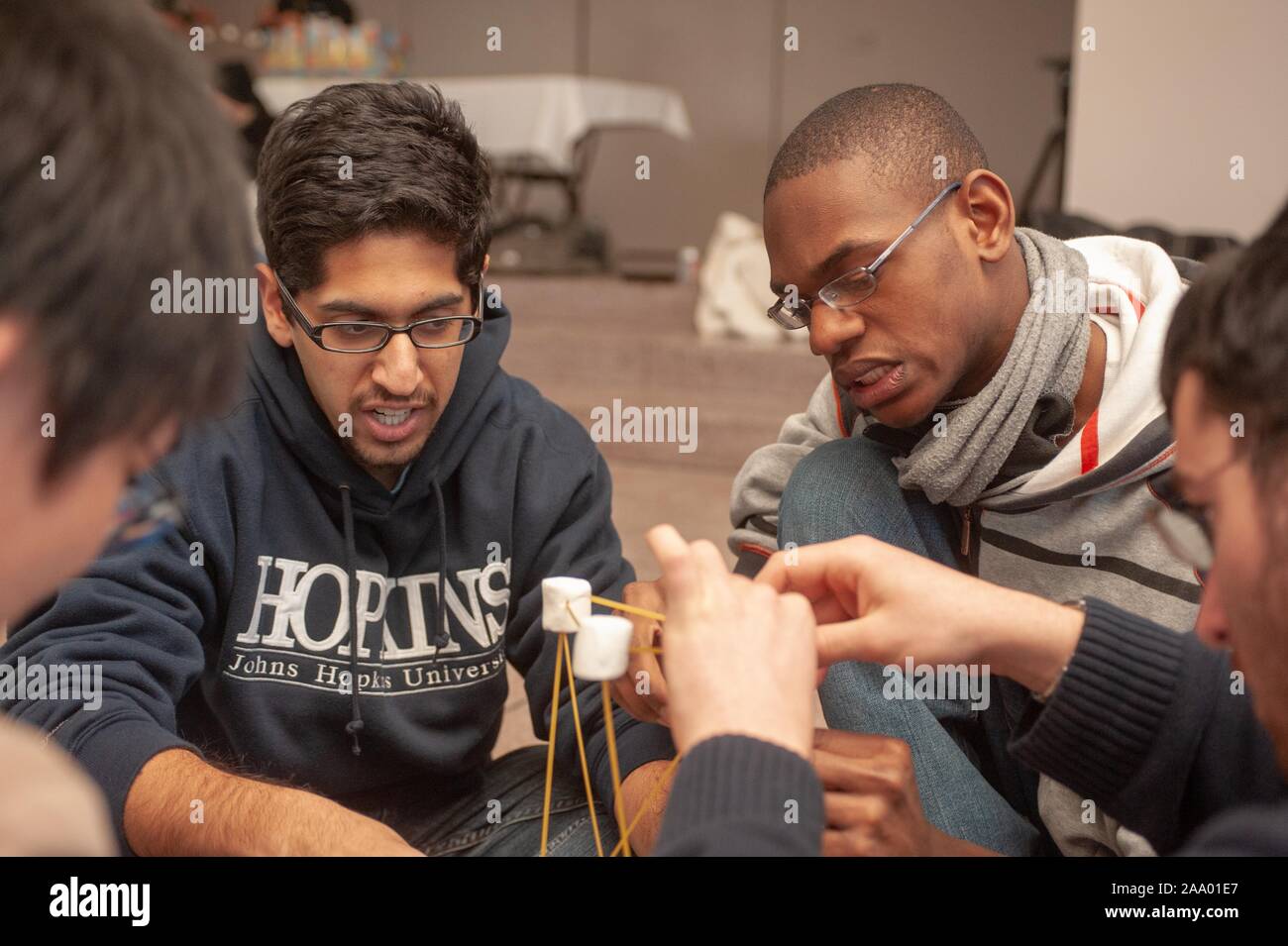 Close-up shot of a team of students building a tower constructed from spaghetti and marshmallows during the annual Whiting School of Engineering Tower of Power event, at the Johns Hopkins University, Baltimore, Maryland, February 16, 2009. From the Homewood Photography Collection. () Stock Photo