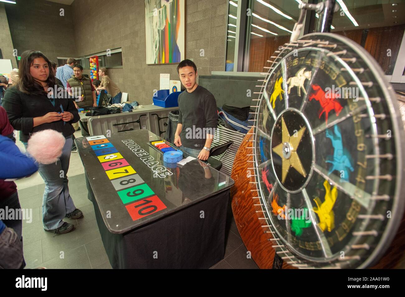 Slightly angled shot of people watching a home-made 'Horse Race' game wheel spin during an 'Engineering Carnival' at the Johns Hopkins University, Baltimore, Maryland, February 21, 2009. From the Homewood Photography Collection. () Stock Photo