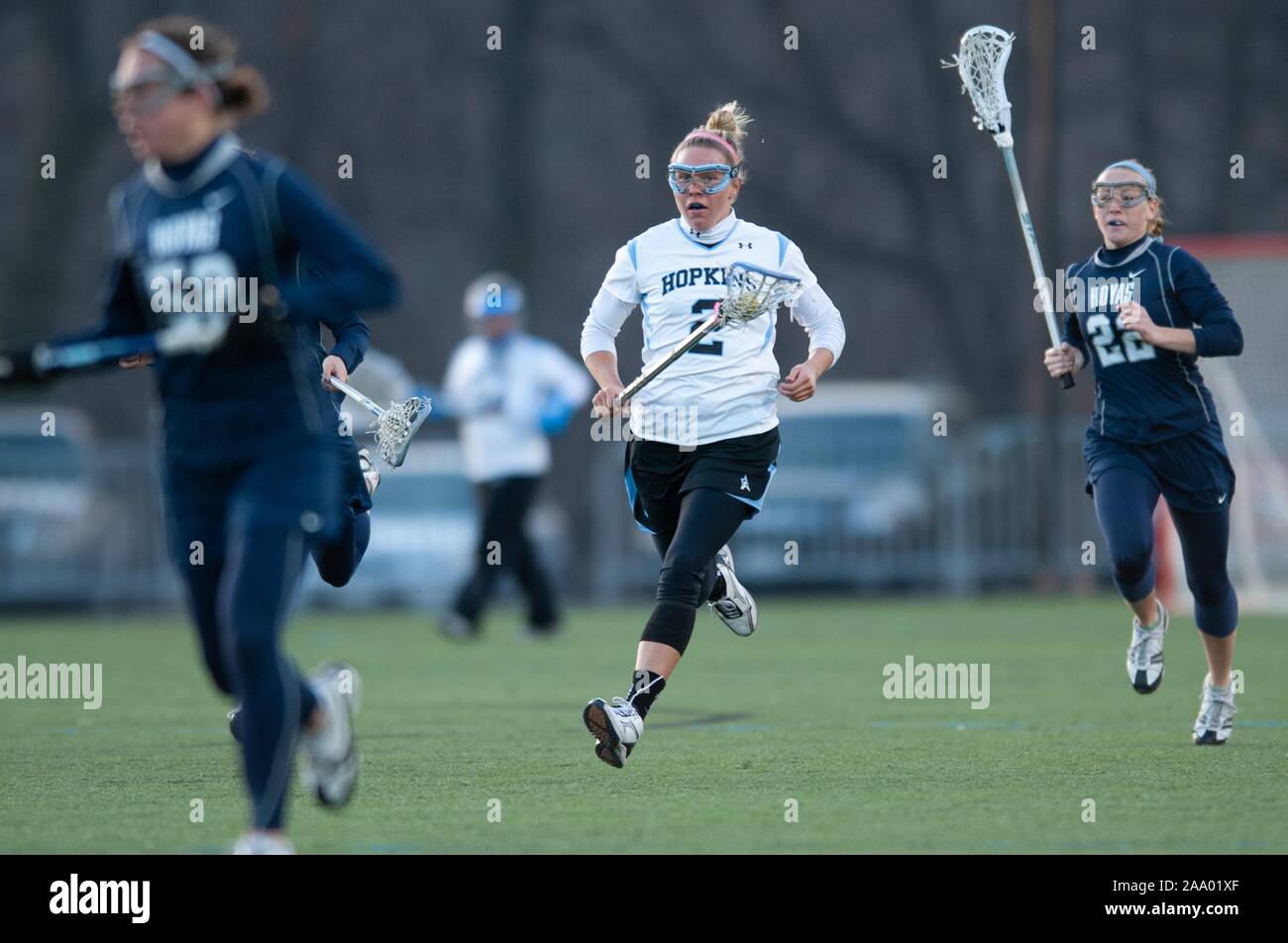 A Johns Hopkins University Women's Lacrosse player, runs, cradling the ball in her net, while being pursued by an opponent during a match with Georgetown University, February 25, 2009. From the Homewood Photography Collection. () Stock Photo