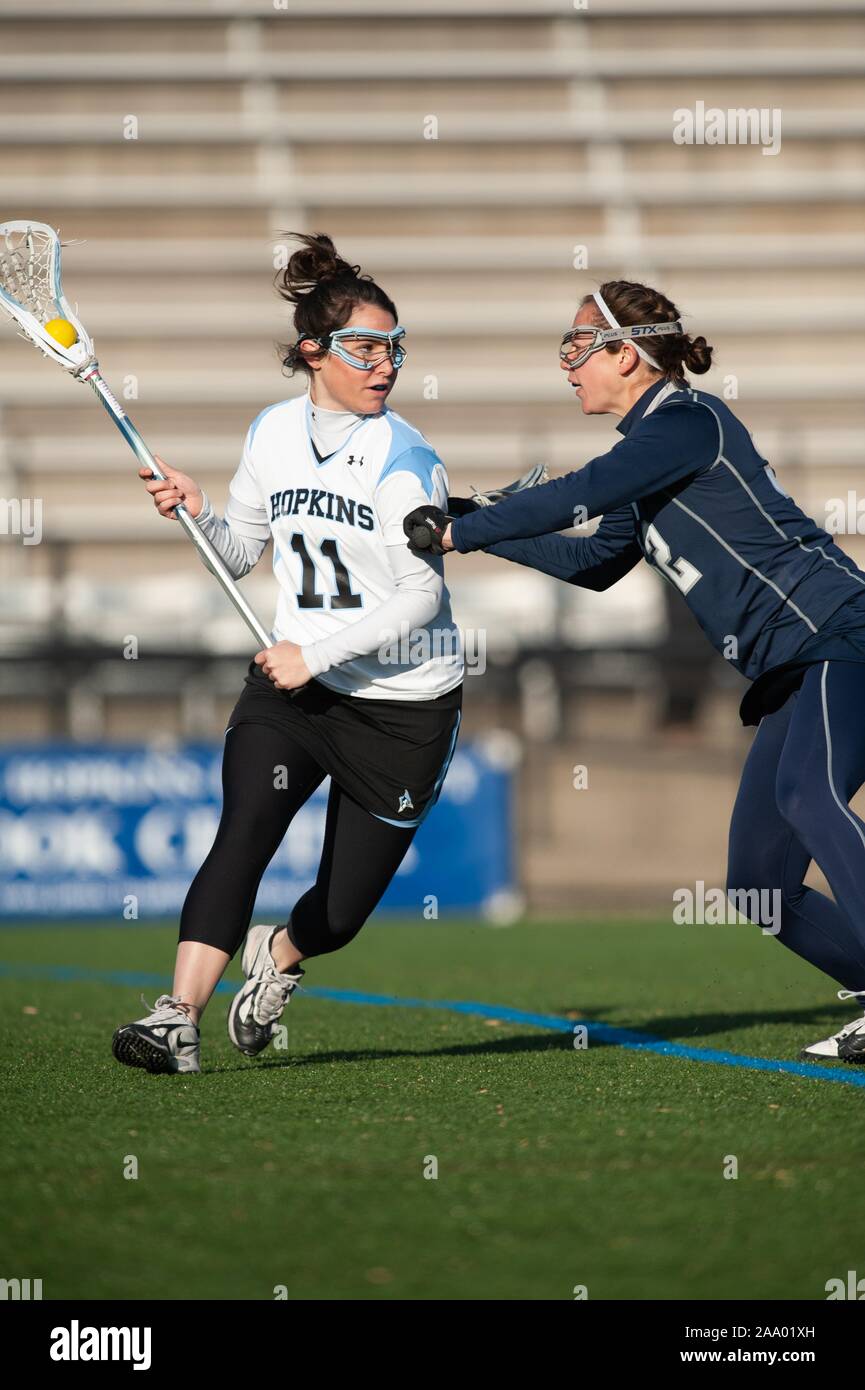 An opponent tries to check a Johns Hopkins University Women's Lacrosse player who cradles the ball in her net during a match with Georgetown University, February 25, 2009. From the Homewood Photography Collection. () Stock Photo