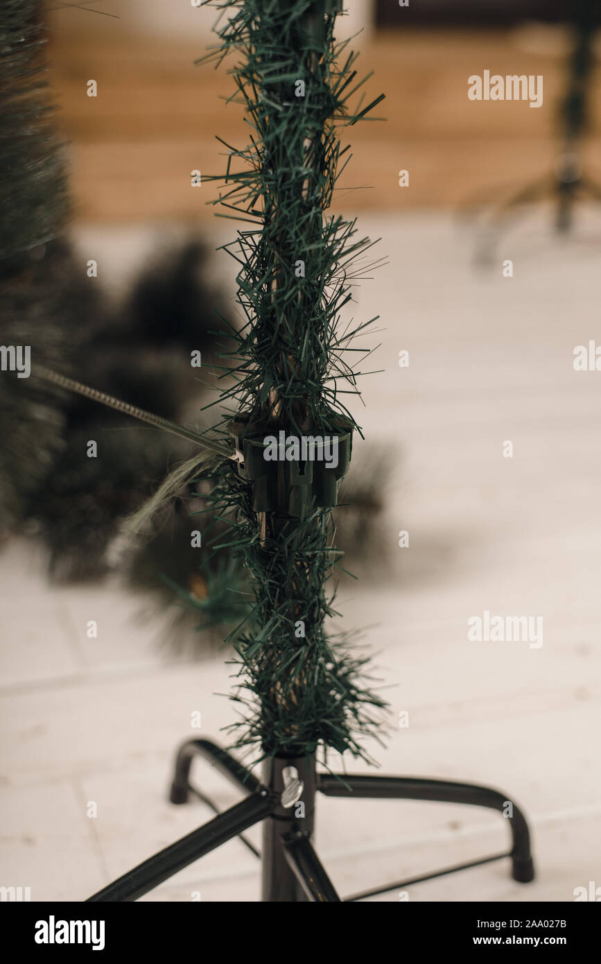 Man collects artificial Christmas tree at home. The stage of Assembly