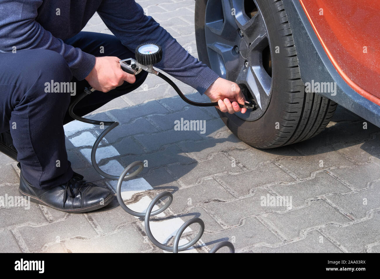 Car service. Man checks pressure in car tires. Hand on auto tire valve