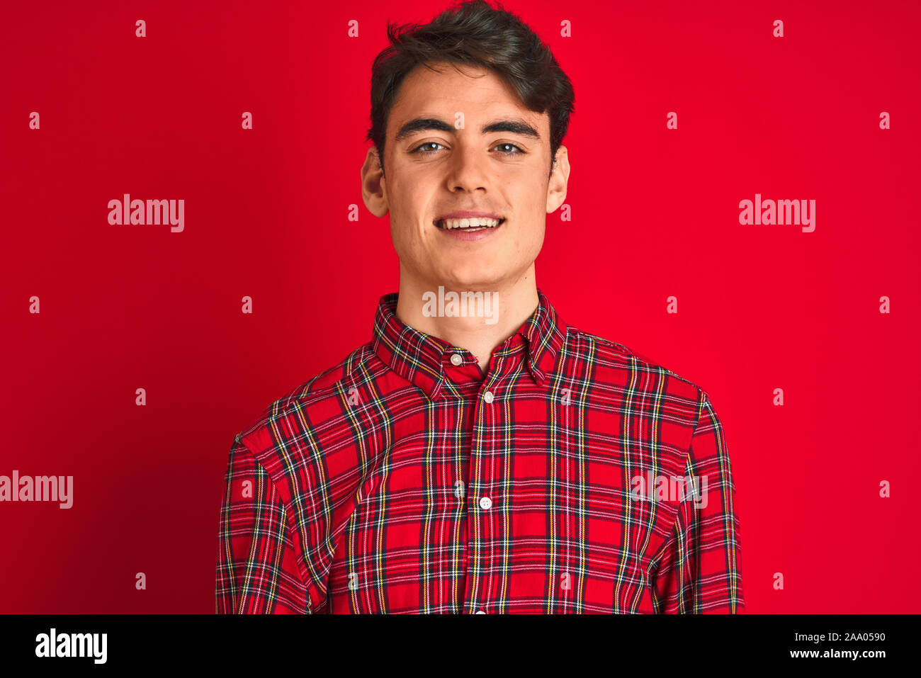 Teenager boy wearing red shirt standing over isolated background with a