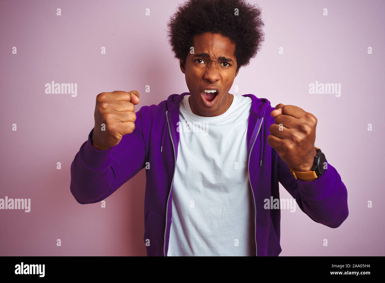Young African American Man Wearing Purple Sweatshirt Standing Over
