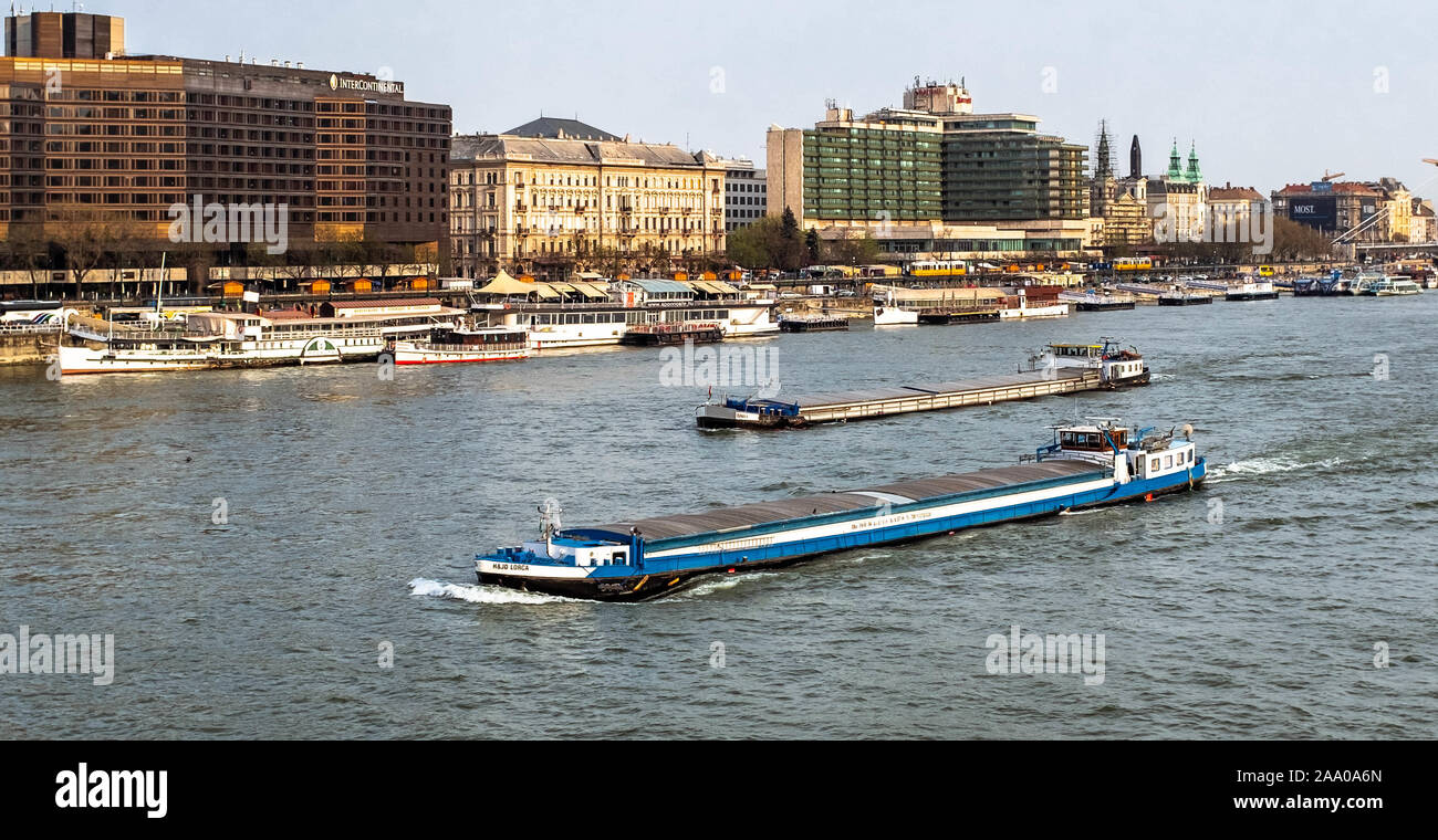 Two river cargo ships sailing in Danube with city scene on background. Stock Photo