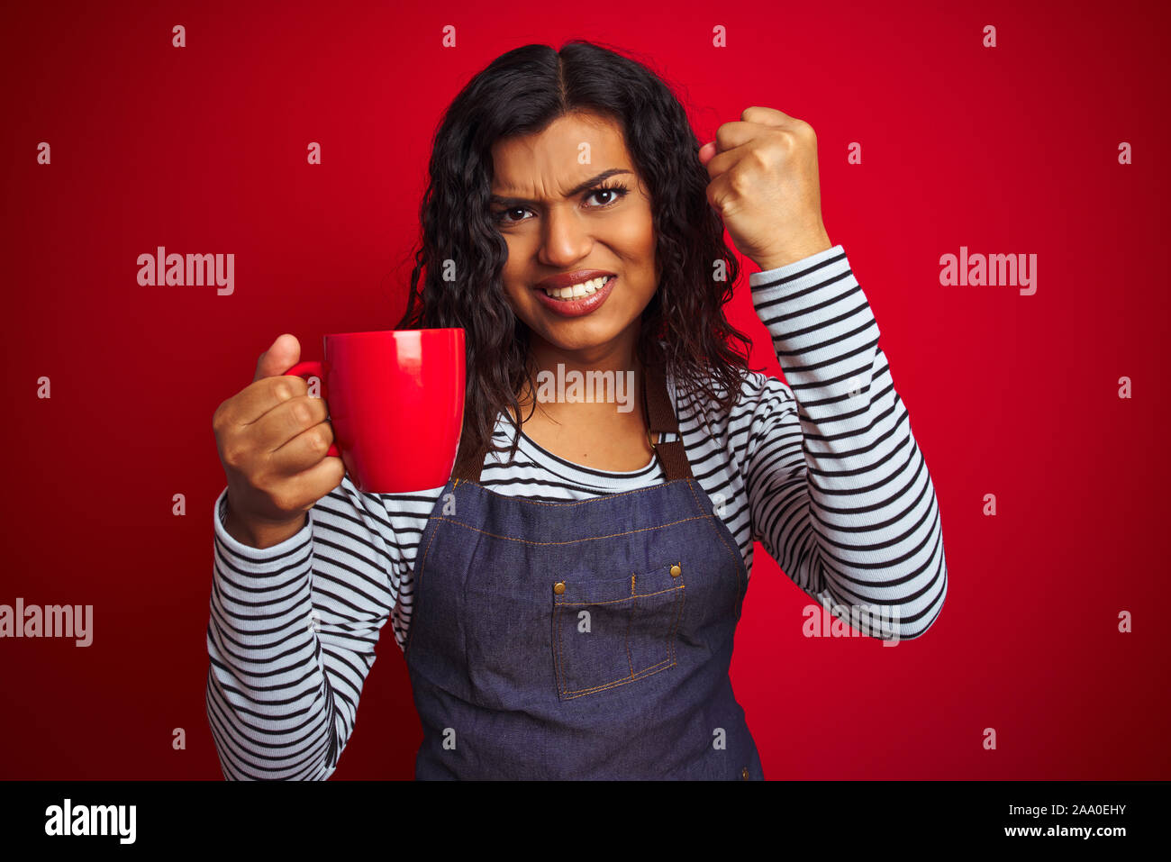 Transsexual transgender barista woman holding cup of coffee over isolated red background annoyed and frustrated shouting with anger, crazy and yelling Stock Photo