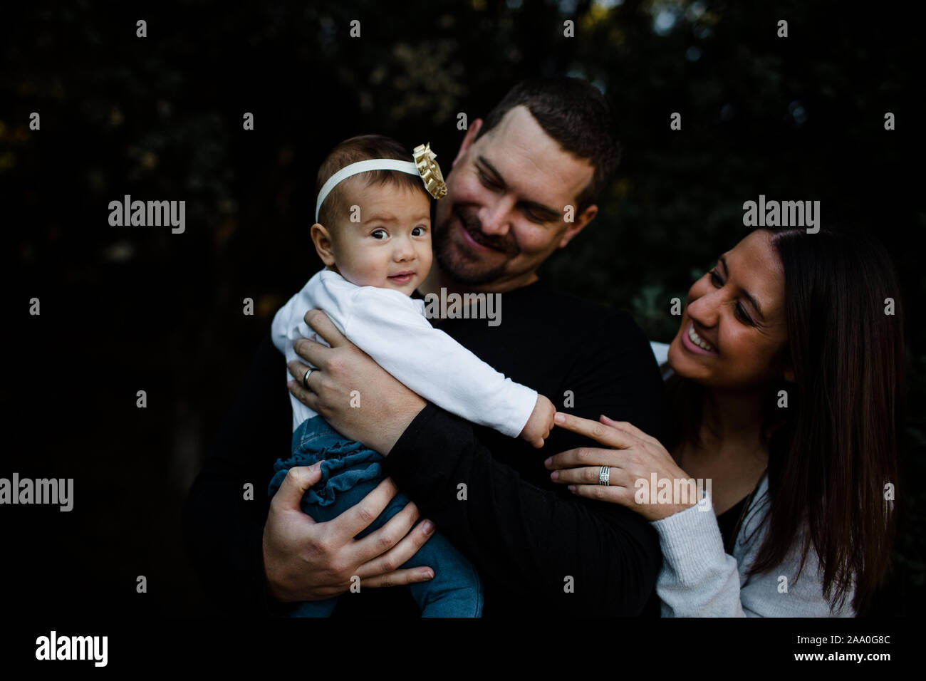 Mom & Dad Smiling at Infant Daughter Stock Photo