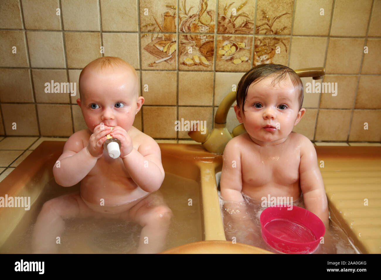10 month old baby girls bathing in the kitchen sink Stock Photo