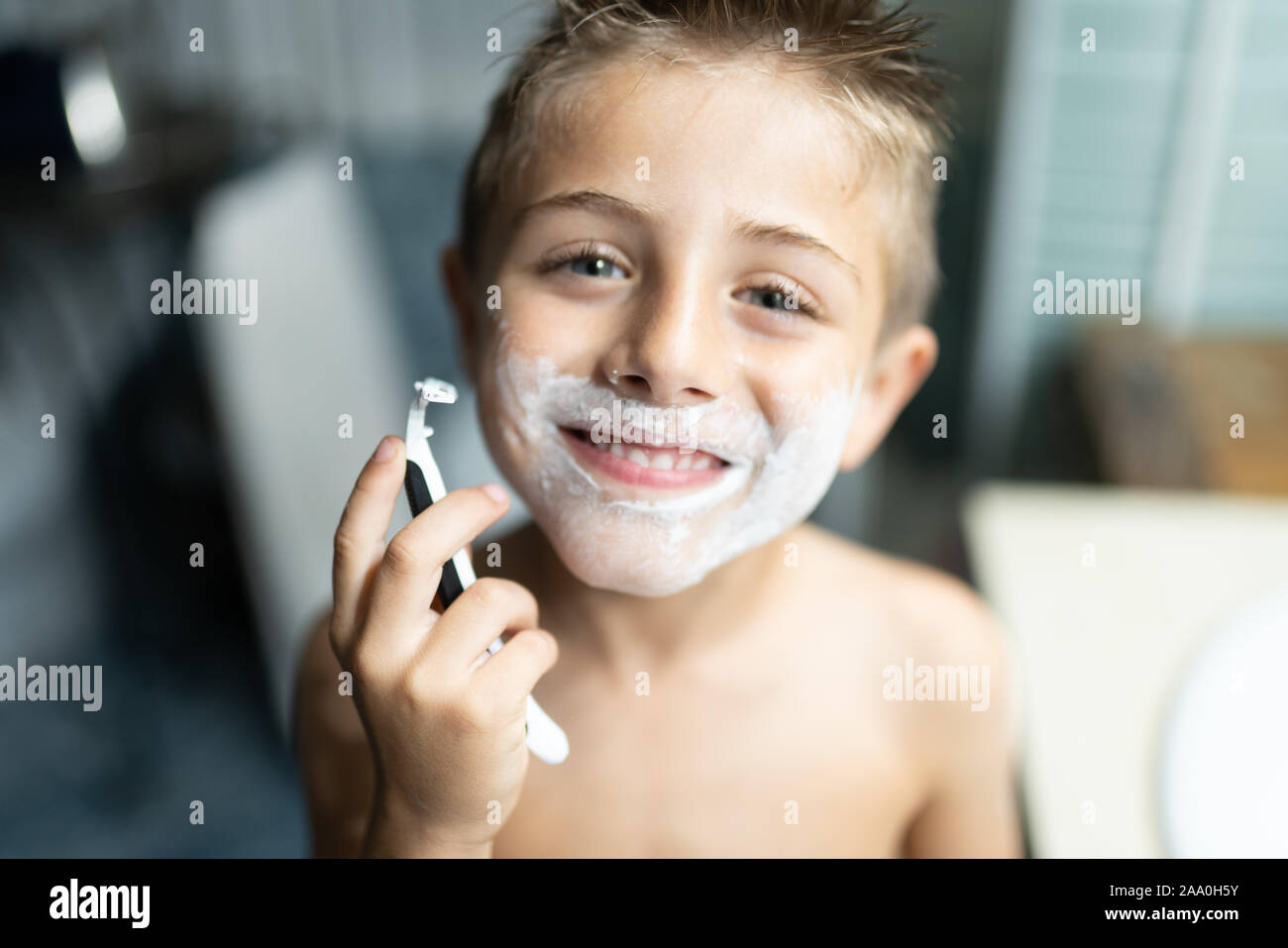 little boy shaving like an adult in the bathroom in front of the mirror