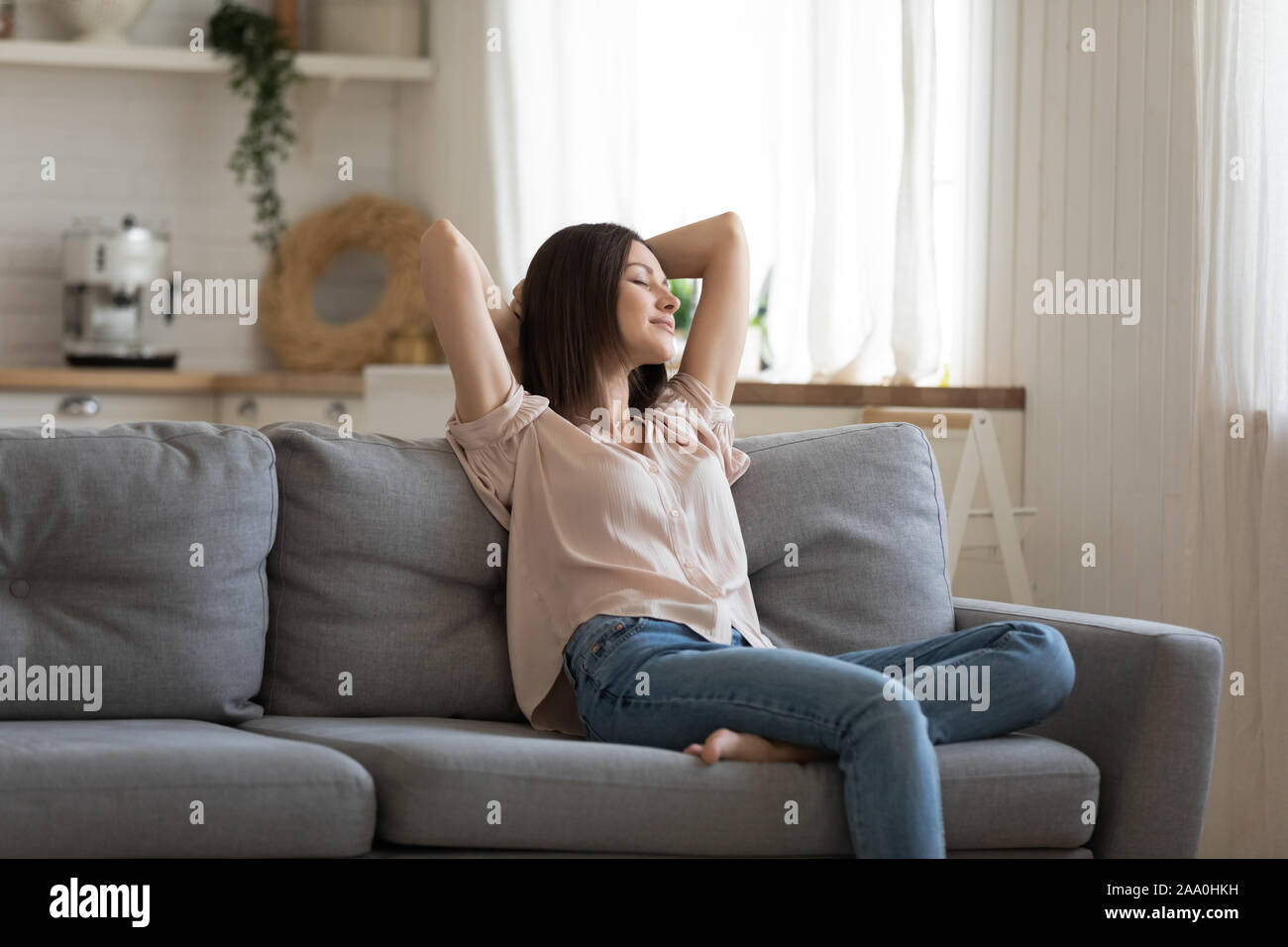 Happy young woman lying on couch in modern living room Stock Photo - Alamy