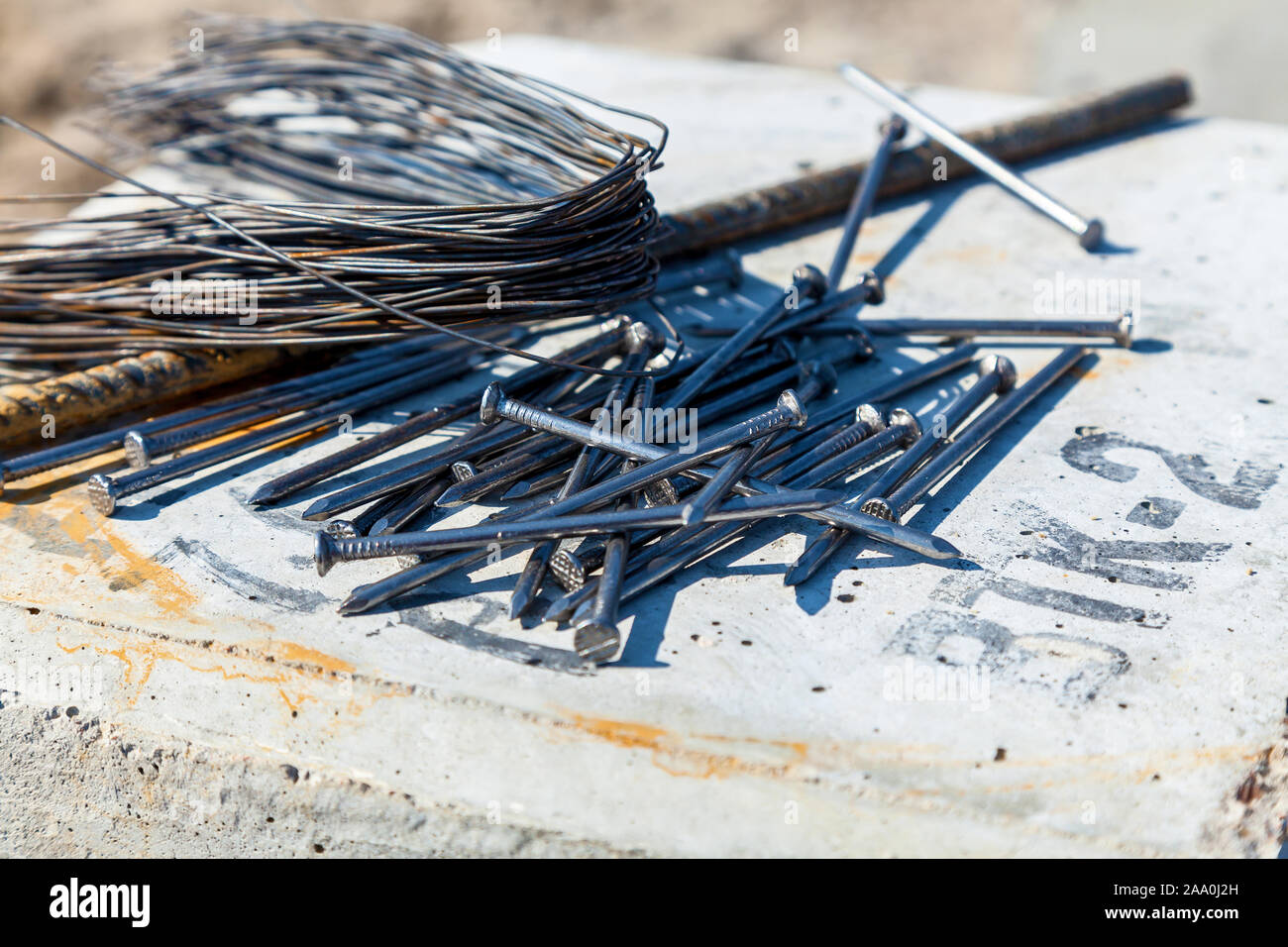 Nails are lying down on the concrete slab next to wire and steel rod Stock Photo