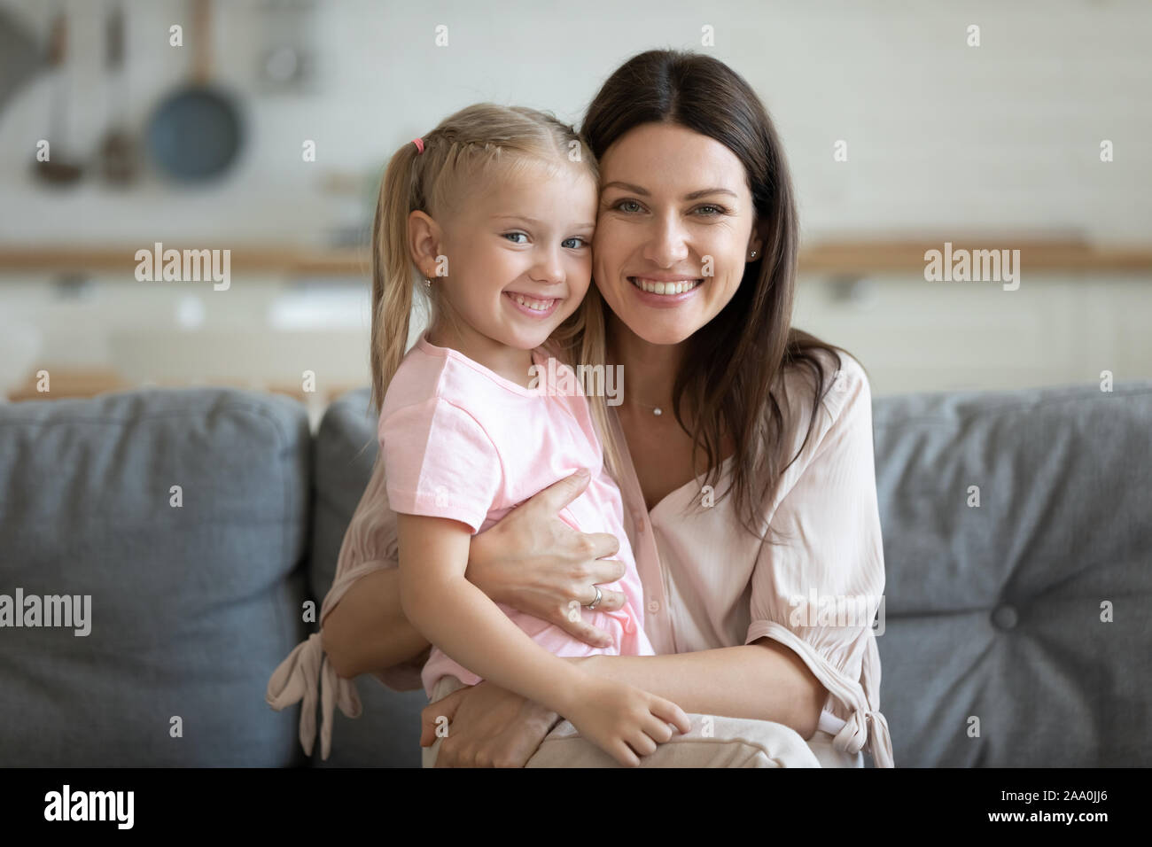Portrait of happy pretty little girl sitting on mommys lap. Stock Photo
