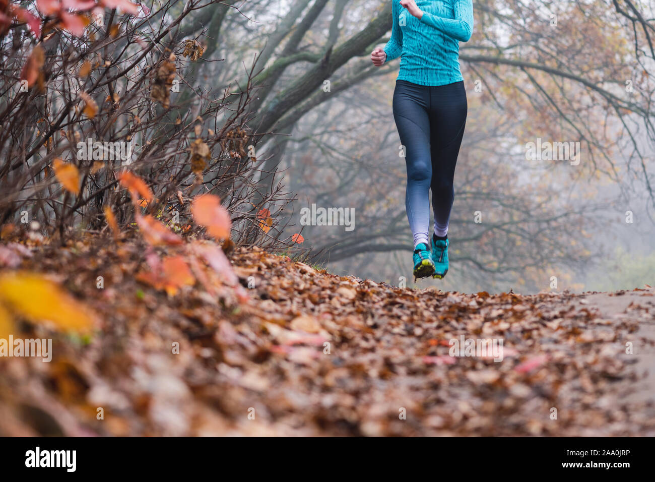 Woman jogging jumping in forest, no face. Fallen foliage on the ground,  autumn foggy morning. Shooting point from below. Flying runner Stock Photo  - Alamy