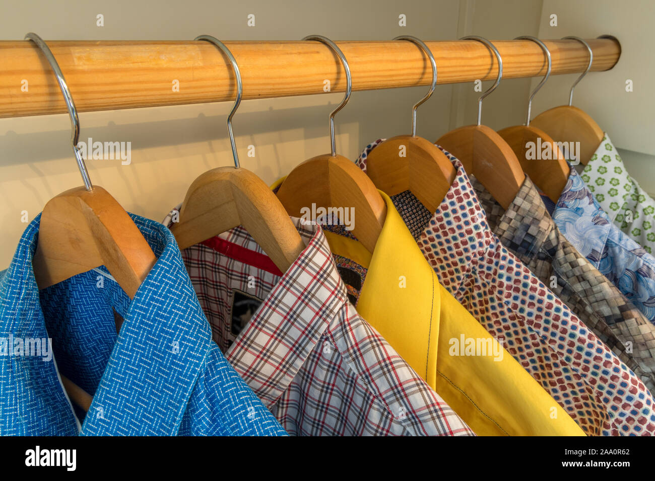 Colorful fresh cloths dress shirt hanging on coat hangers in closet Stock Photo