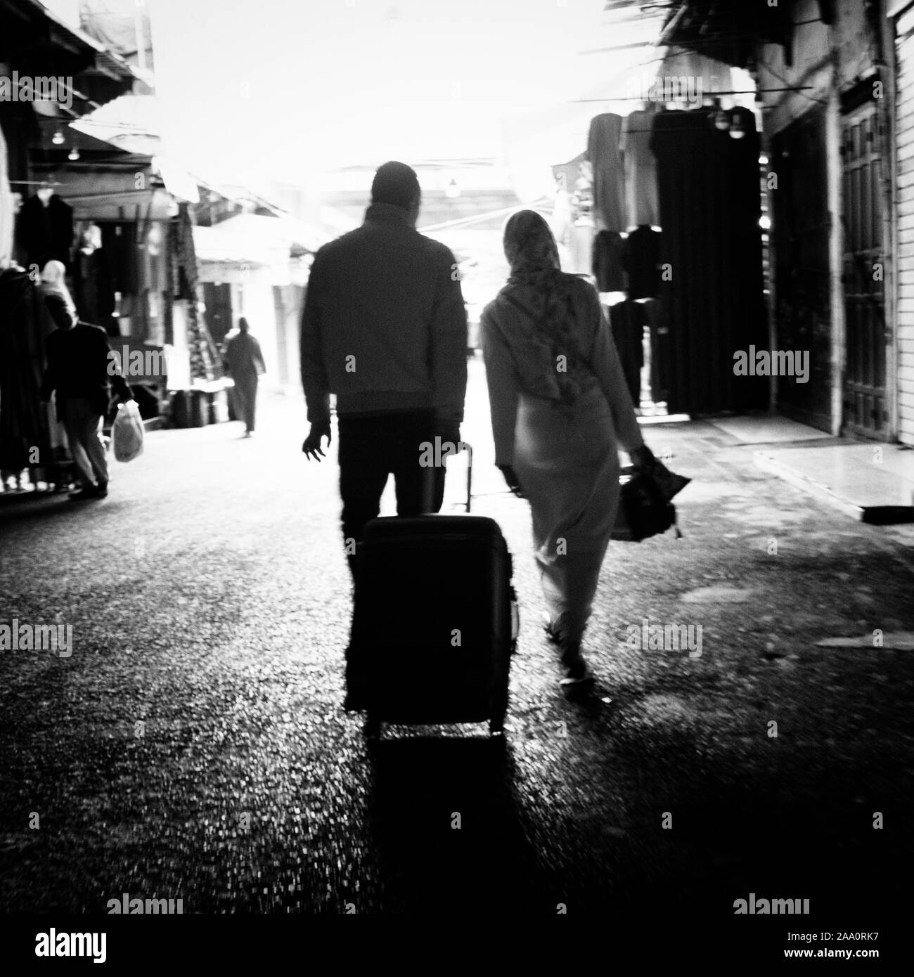 Fez, Morocco. November 9, 2019.  a couple with suitcase in hand walking in the street in a monochrome image Stock Photo