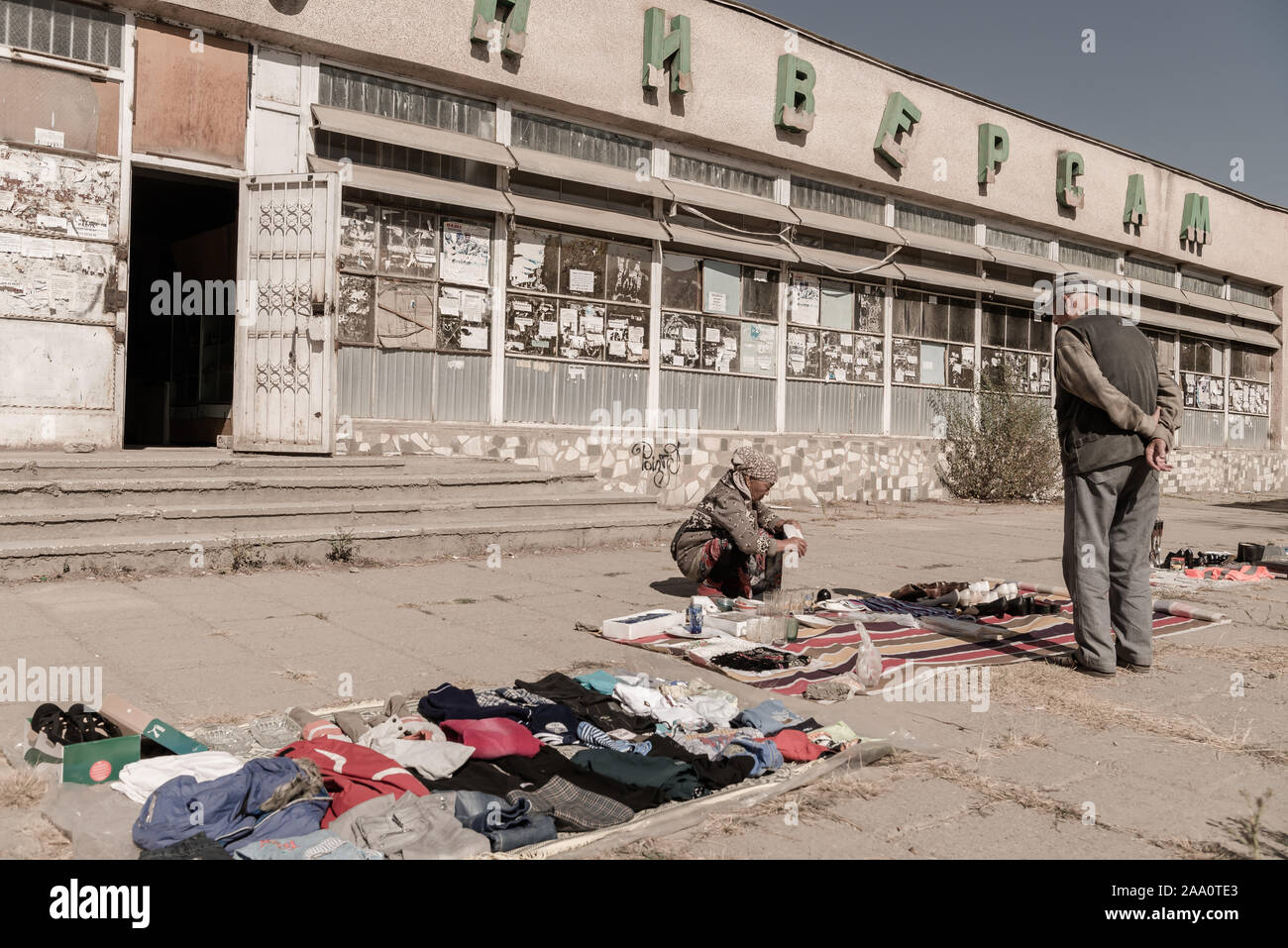 Pensioner selling her possessions on pavement, Mailluu Suu, Kyrgyzstan Stock Photo