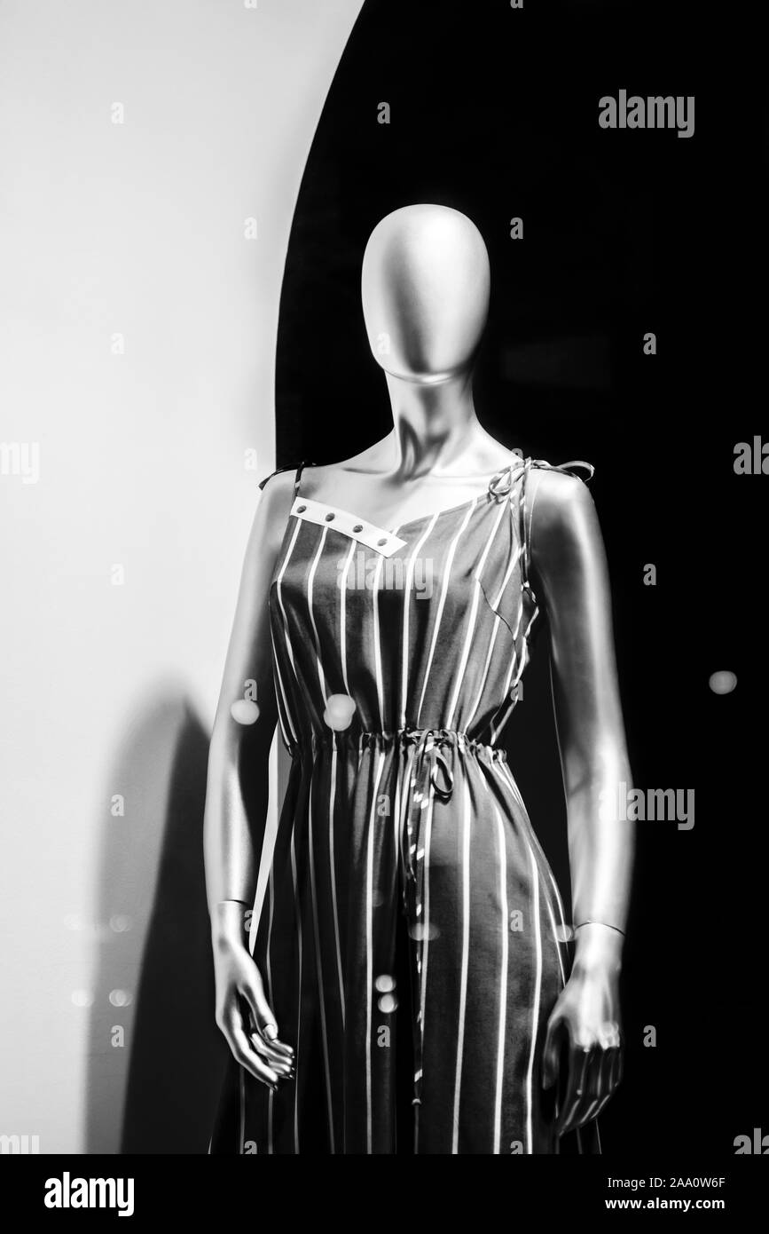 Mannequin standing in store window display of women's casual clothing