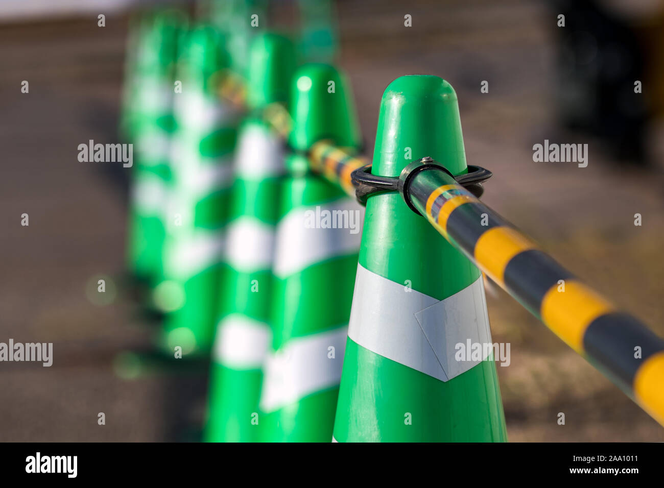 Green safety cones with white stripes placed in a row, selective focus Stock Photo Alamy
