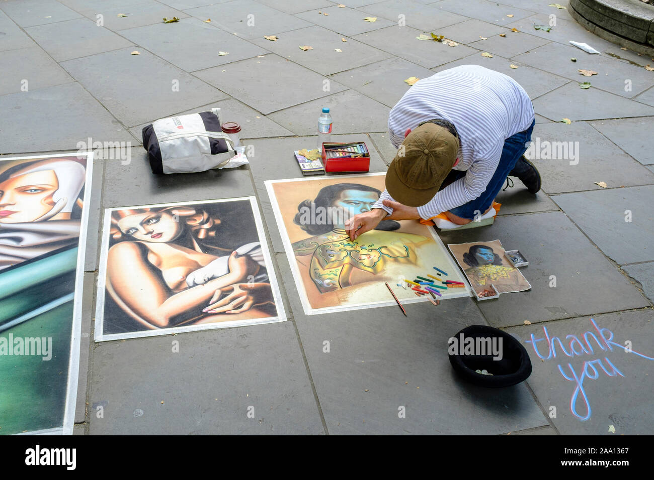 Pavement artist at work on London street reproducing paintings by Vladimir Tretchikoff and Tamara de Lempika. Stock Photo