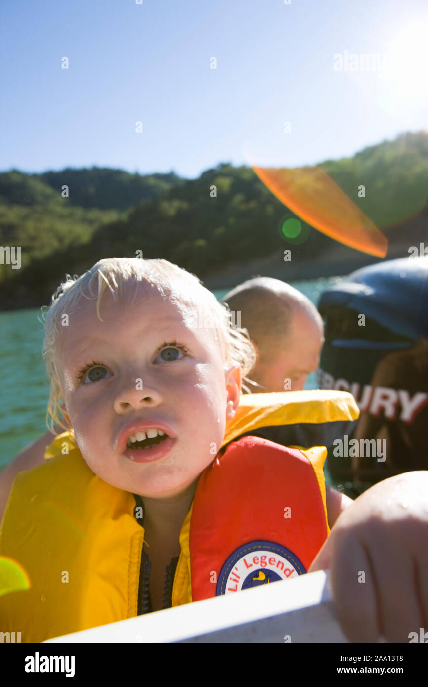 Young boy looking amazed while wearing a lifejacket while on a boat ride. Stock Photo