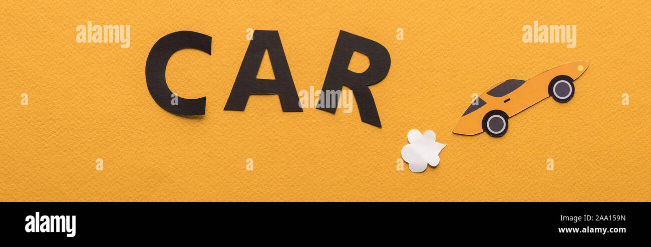 top view of paper cut sports car with exhaust gas and black car lettering on orange background, panoramic shot Stock Photo