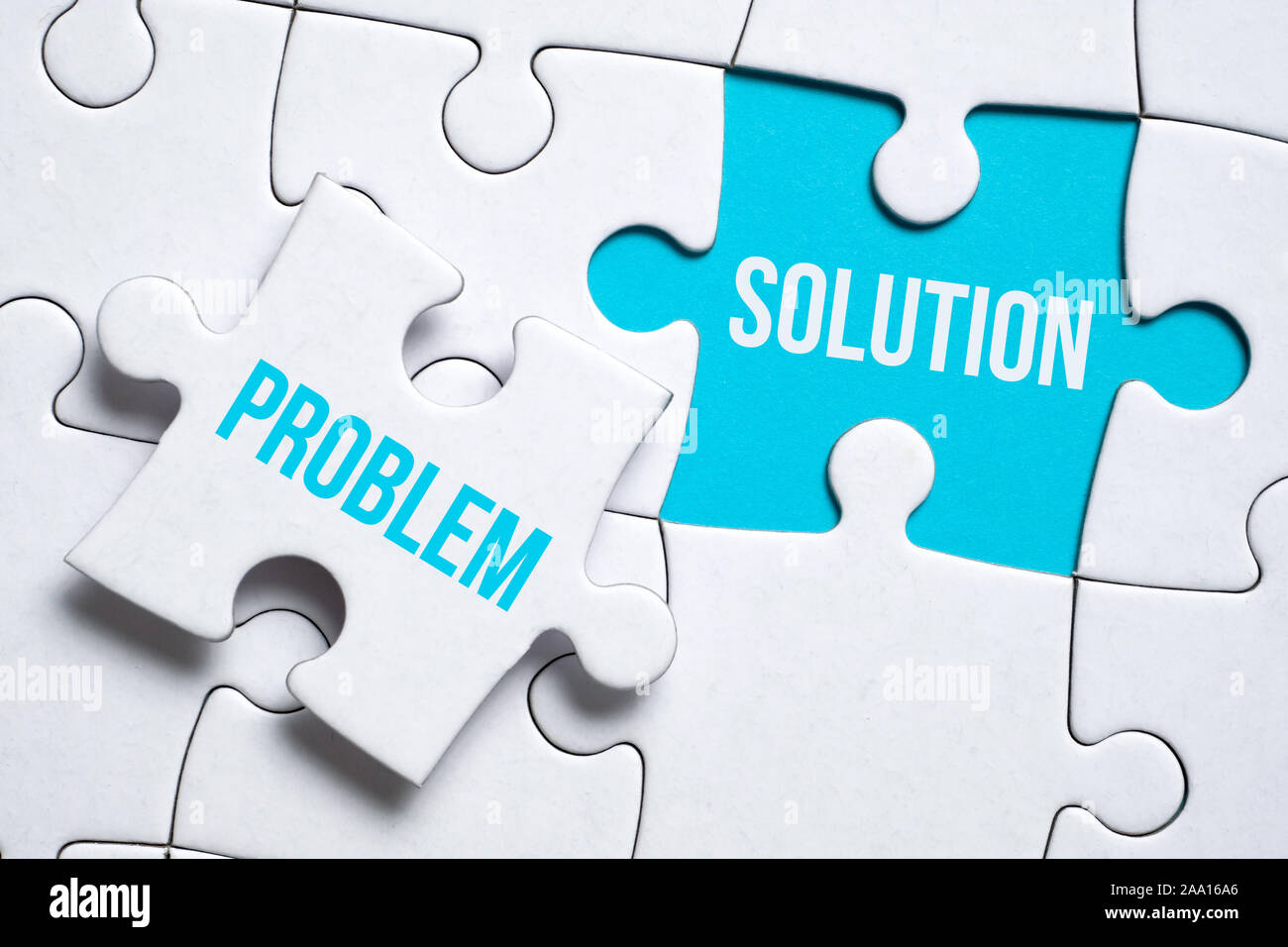 Concept solution to the problem. A piece of the puzzle with the inscription  holds the fingers of a man next to another on a blue background. Close up  Stock Photo - Alamy