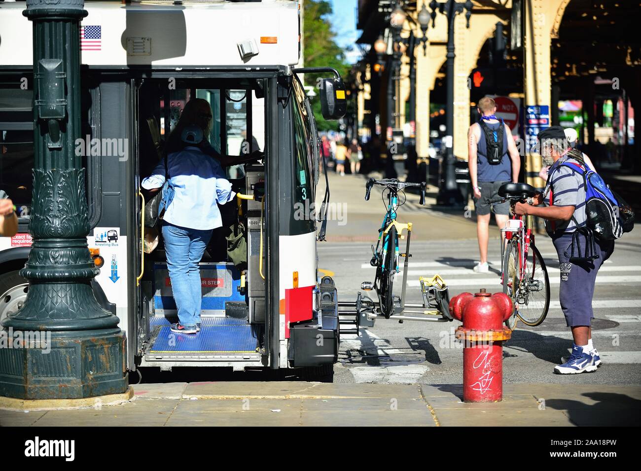 Chicago, Illinois, USA. Prior ot boarding the bus, a passenger mounts his bicycle on a CTA bus