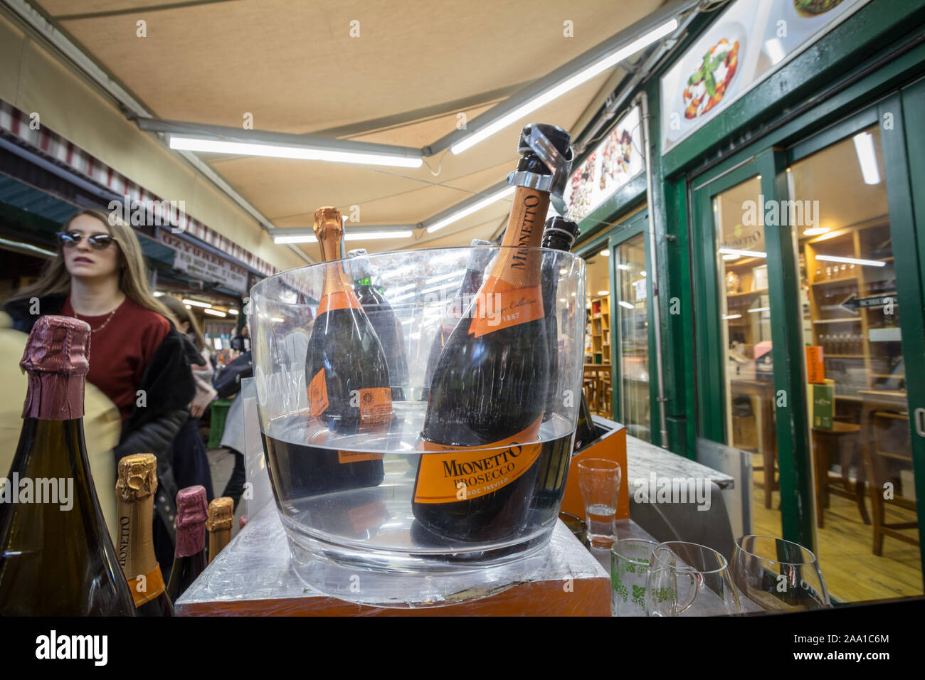 VIENNA, AUSTRIA - NOVEMBER 6, 2019: Prosecco bottles on display in an ice bucket in a Vienna market with people tasting the wine behind. Prosecco is a Stock Photo