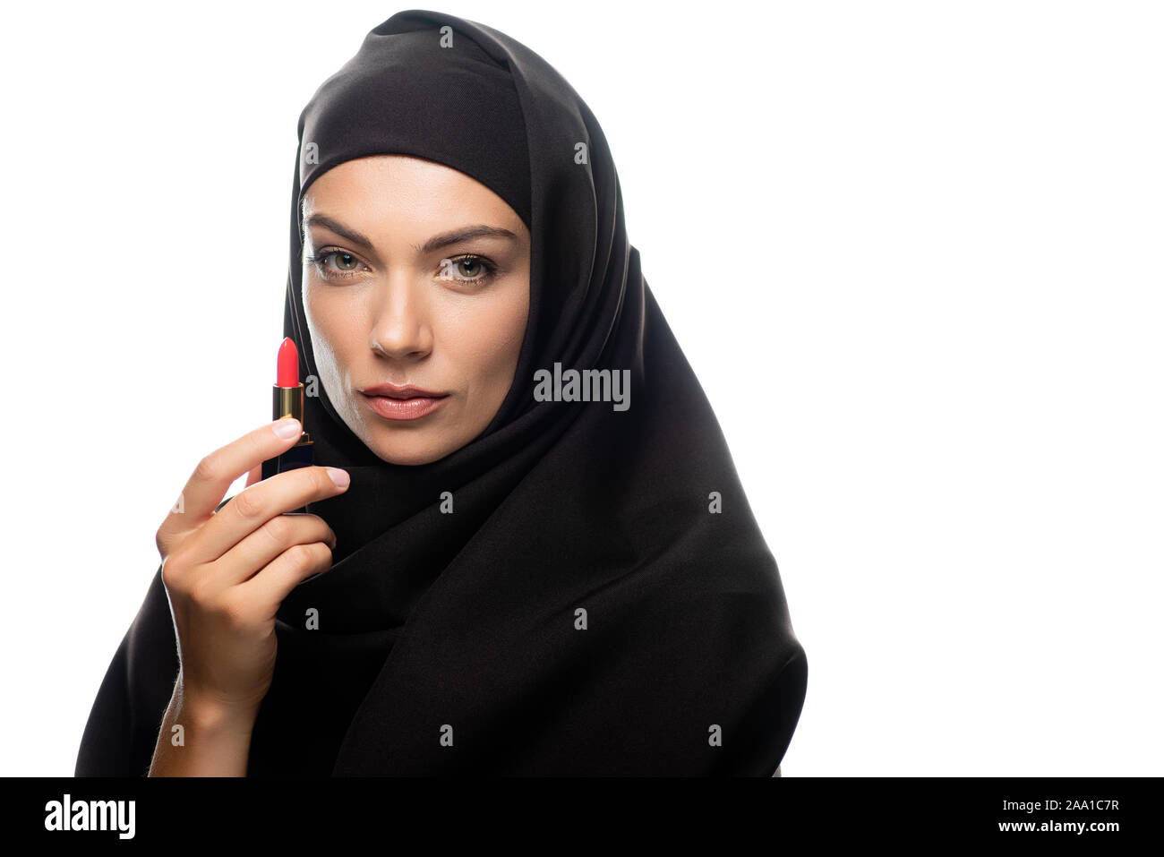 young Muslim woman in hijab holding red lipstick isolated on white ...