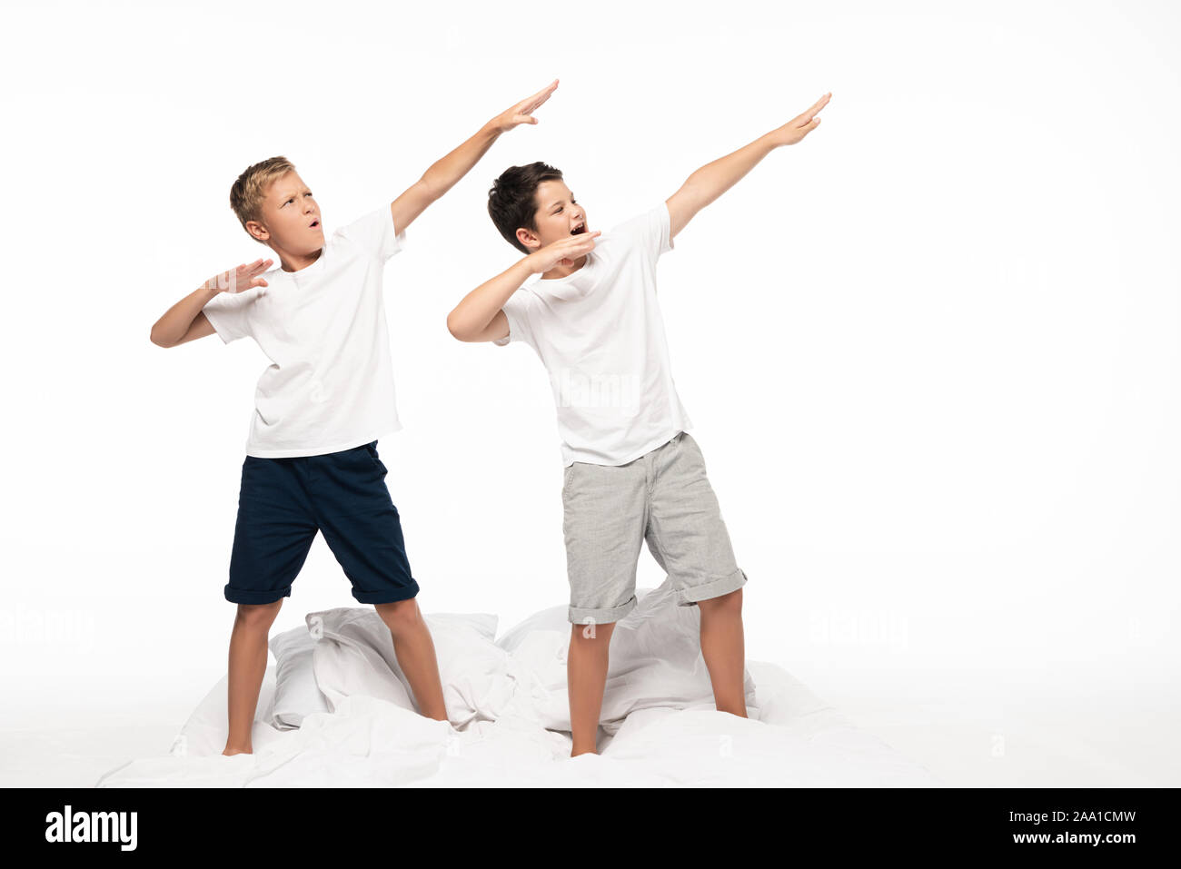 two brothers imitating archery while standing on bed isolated on