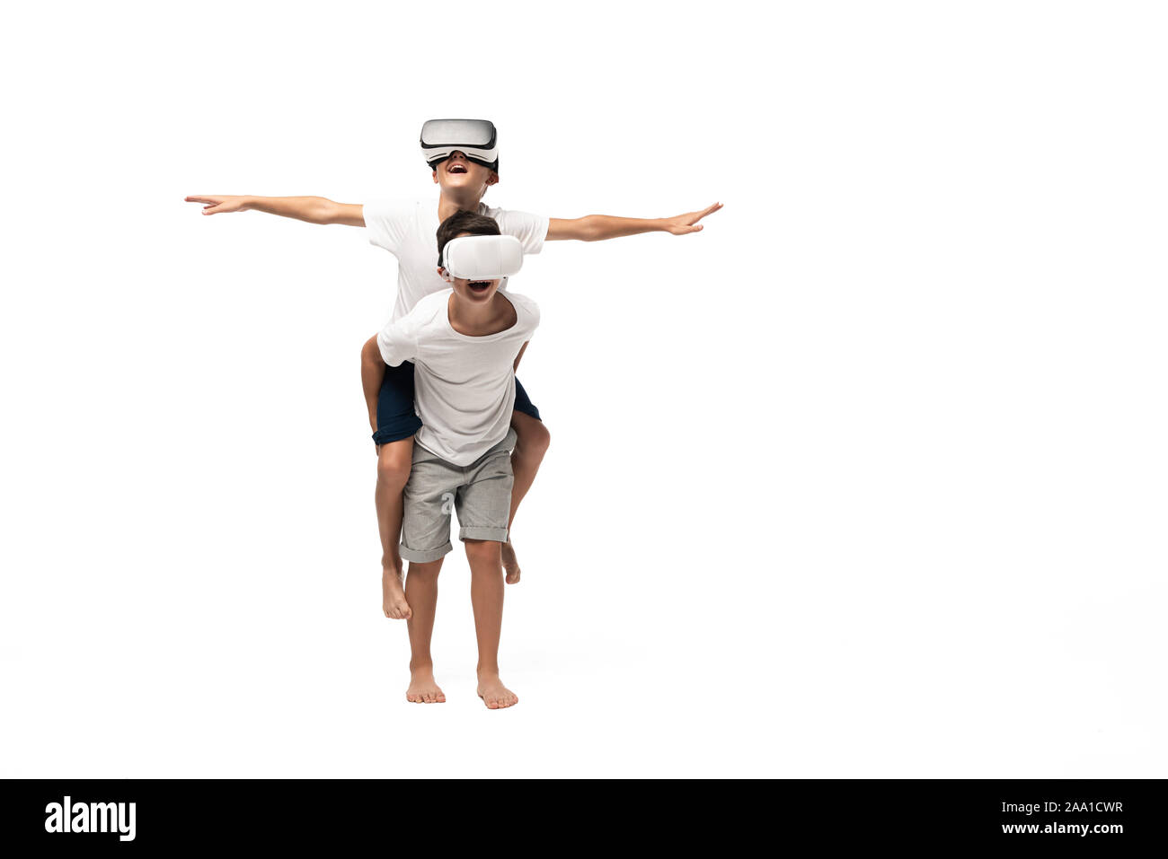 smiling boy using vr headset while piggybacking on brothers back and imitating flying on white background Stock Photo