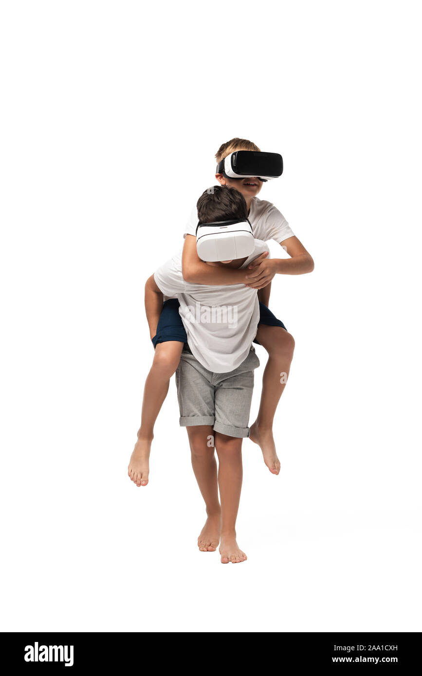 boy piggybacking brother while using vr headsets together on white background Stock Photo