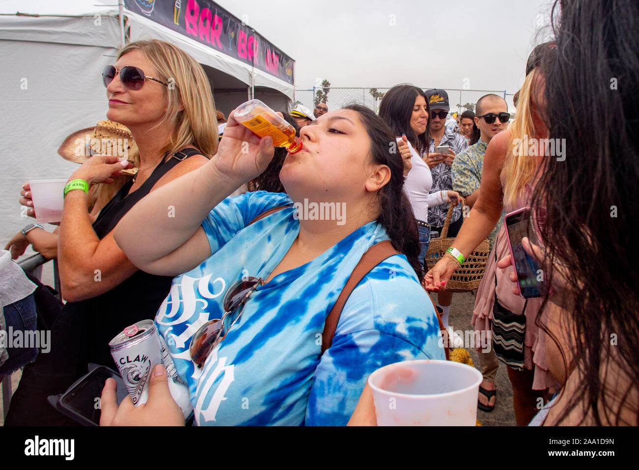 Waiting for an outdoor concert in Huntington Beach, CA, to begin, a lady in the audience drinks an anticipatory toast. Stock Photo
