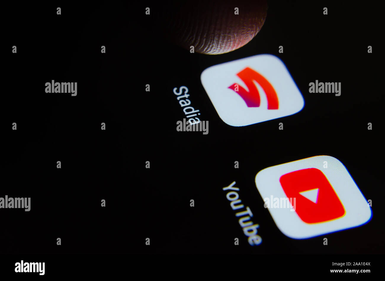 Google Stadia and Youtube apps on the smartphone screen and a finger above it prepared to launch Stadia. Stock Photo