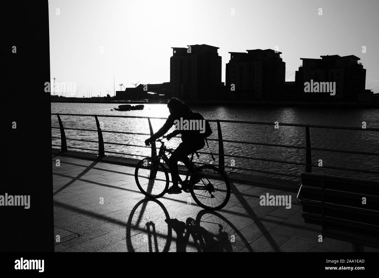 Cyclist commute on an early winter morning Swansea marina in silhouette Stock Photo